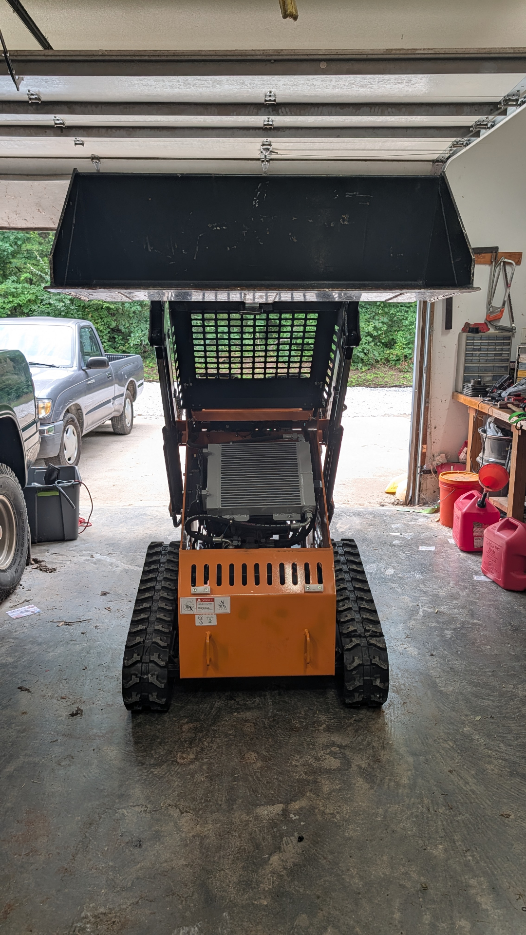 Mini skid-steer loader with bucket raised in the shop
